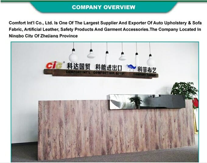 Prijemni prostor Comfort Int'l Co., s drvenim stolom i visećim svjetlima, sa znakom s popisom djelatnosti tvrtke.