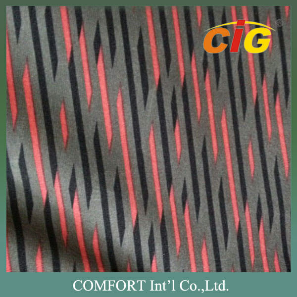 Tekstuurne kangas diagonaalsete tumepruunide triipude ning hajutatud roheliste ja oranžide ruutudega, millel on logo ja ettevõtte nimi: comfort int'l co., ltd.