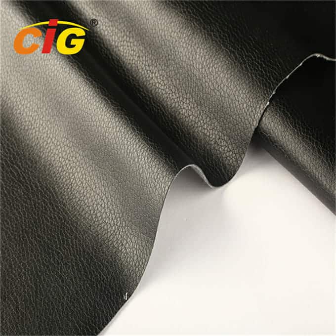 Close-up view of a sheet of black synthetic leather with a textured surface, partially folded to show the white underside.