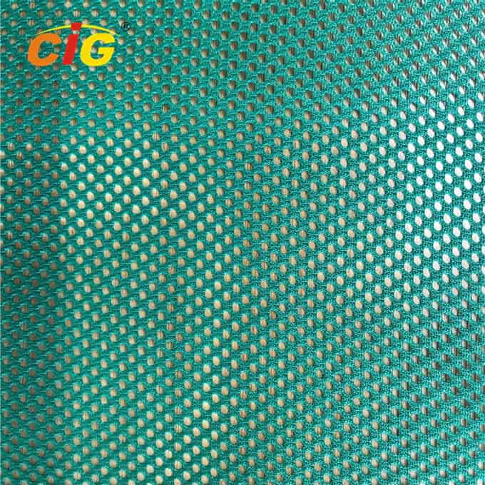 Vista cercana de una tela de malla verde azulado con un patrón repetido de pequeños círculos, que muestra la textura y el tejido.