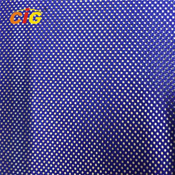 Primo piano di un tessuto blu strutturato con un motivo punteggiato e un logo "cig" giallo nell'angolo in alto a sinistra.