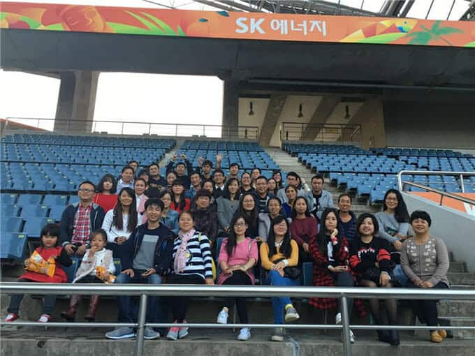 Một nhóm đông người đang tạo dáng chụp ảnh trên khán đài của một sân vận động thể thao với tấm biển "sk 에너지" ở phía sau.