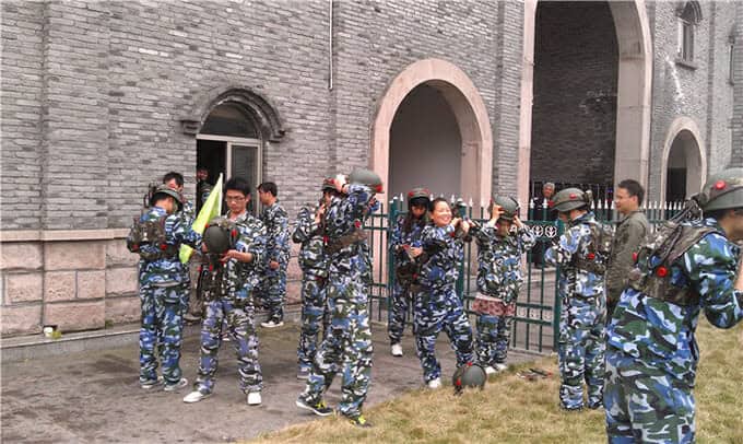 Войници в камуфлажни униформи, участващи в стрелба с лък; някои насочват лъковете си, докато други приготвят стрели.