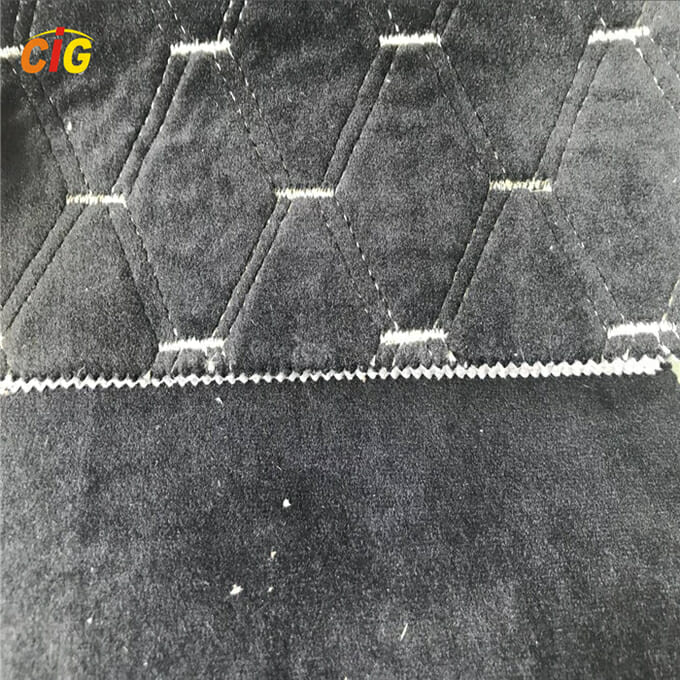 ภาพระยะใกล้ของผ้าควิลท์สีเทาที่มีรูปแบบการเย็บแบบสามเหลี่ยม