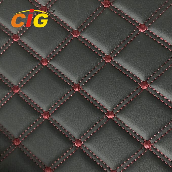 Tampilan jarak dekat dari kain pelapis jahitan berlian hitam dengan jahitan merah dan kancing merah di persimpangannya, ditandai dengan logo "cig".