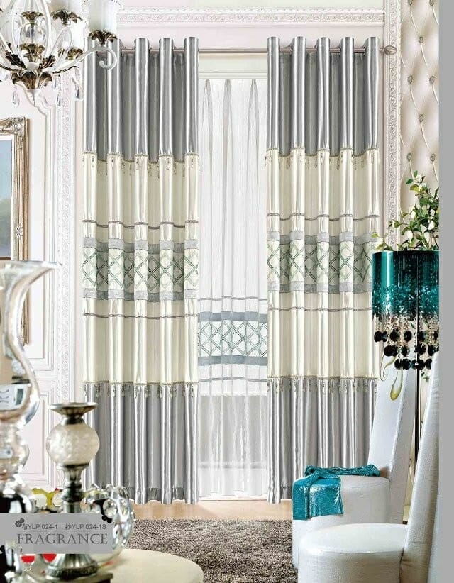 Elegant vardagsrum med utsmyckade gardiner i nyanser av grädde och grått, golvlånga fönster och lyxig inredning, inklusive en kristallkrona och lyxiga möbler.