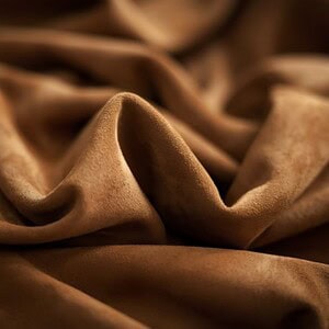 Close-up of soft, brown suede fabric highlighting its texture and flexibility.